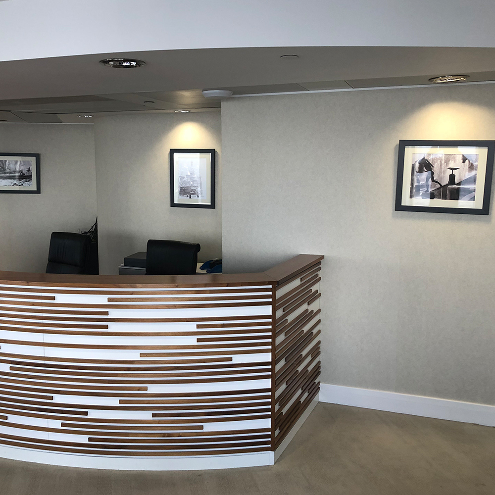 Office refurbishment featuring a contemporary curved reception desk with a unique wood and white slat design.